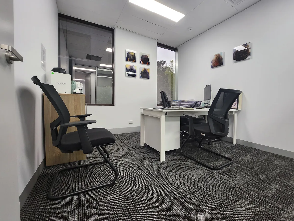 Consultation office with desk, ergonomic chairs and city outlook at the Ashley & Martin cosmetic clinic fitout, Southbank.