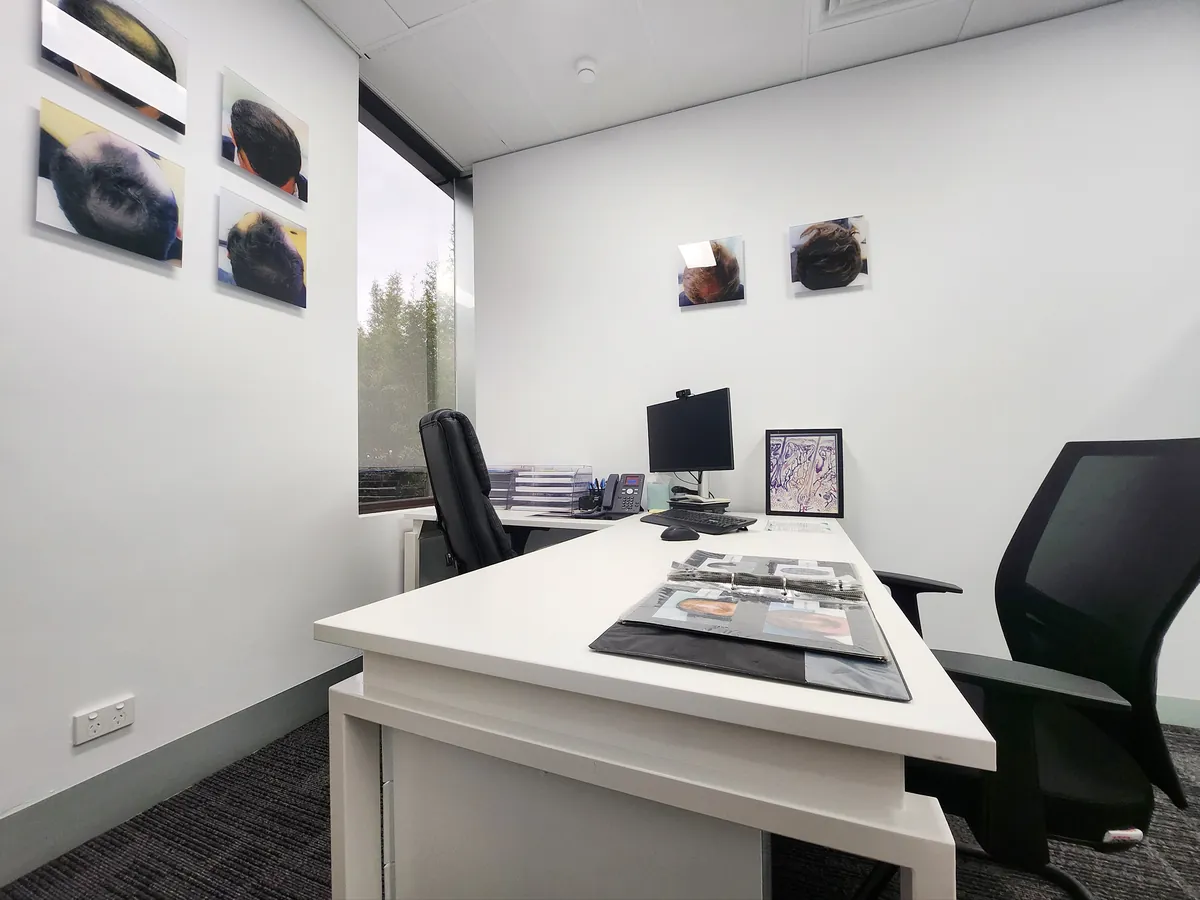 Corner consult office with curved white desk and dual monitors at the Ashley & Martin cosmetic clinic fitout, Southbank.