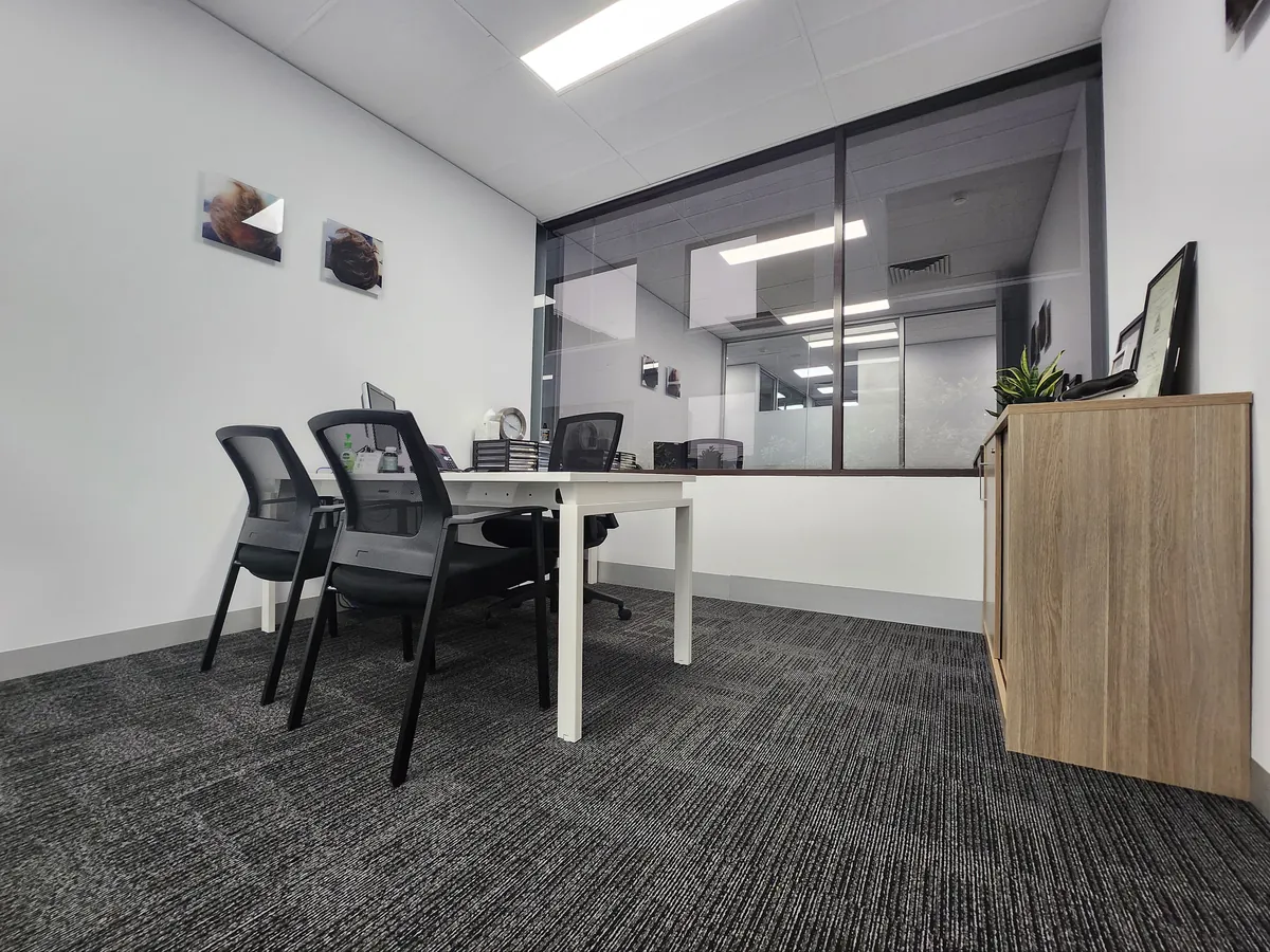 Compact consult room with desk and glass partition to reception at the Ashley & Martin cosmetic clinic fitout, Southbank.