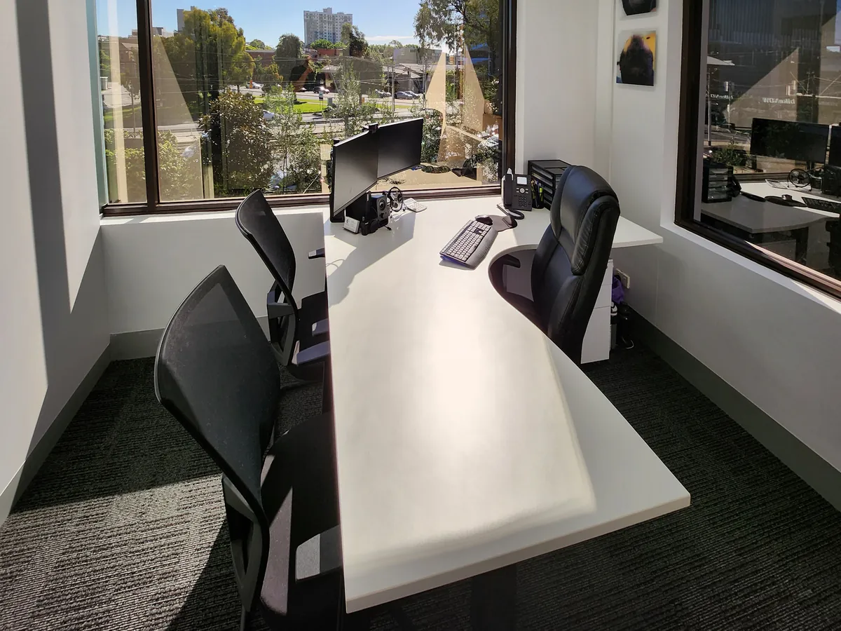 Private consult office with white desk and leafy outlook at the Ashley & Martin cosmetic clinic fitout, Southbank.