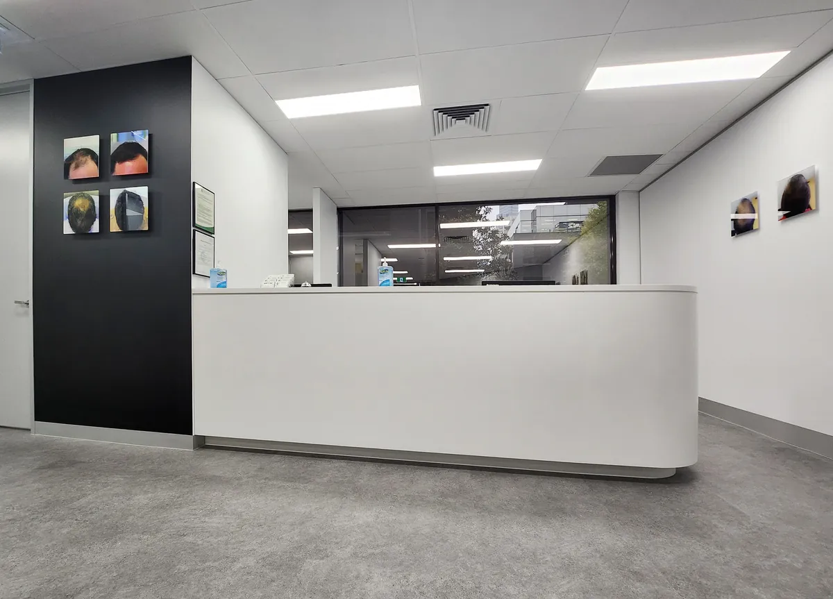 Curved white reception desk with black feature wall and glazing at the Ashley & Martin cosmetic clinic fitout, Southbank.