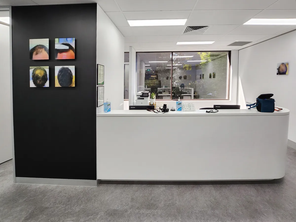 White reception counter with black feature wall and internal window at the Ashley & Martin cosmetic clinic fitout, Southbank.