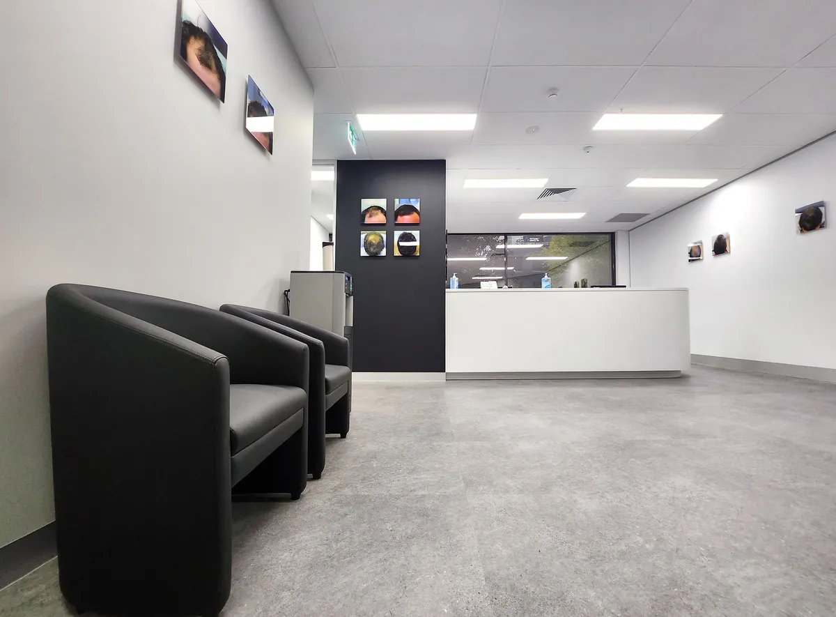 Reception desk and waiting tub chairs with feature wall at the Ashley & Martin cosmetic clinic fitout, Southbank.