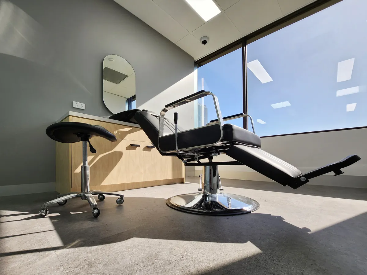 Reclining styling chair and stool with mirror and vanity joinery at the Ashley & Martin cosmetic clinic fitout, Southbank.