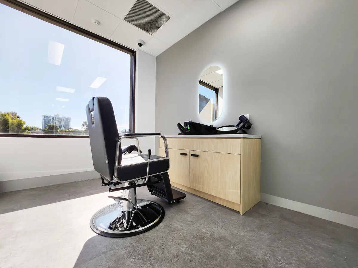 Styling room with barber-style chair, lit mirror and timber joinery vanity at the Ashley & Martin cosmetic clinic fitout, Southbank.