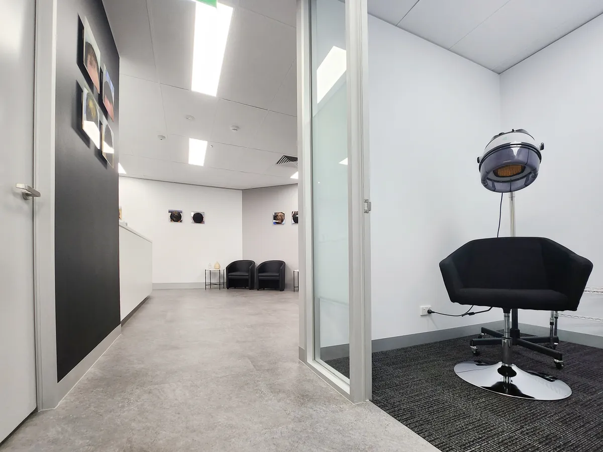 Treatment booth with hooded dryer and styling chair beside reception at the Ashley & Martin cosmetic clinic fitout, Southbank.
