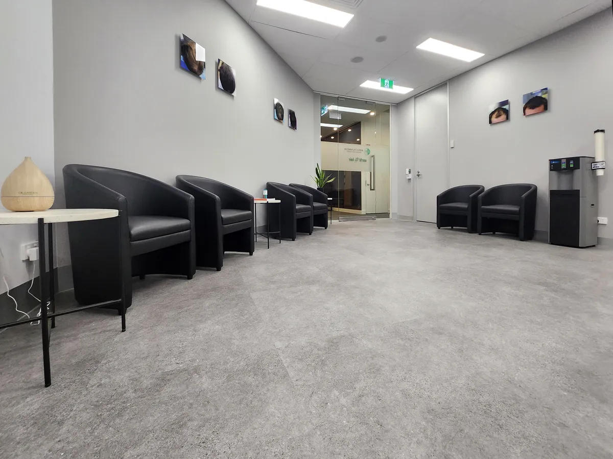 Spacious waiting area with rows of black tub chairs and glazed entry at the Ashley & Martin cosmetic clinic fitout, Southbank.
