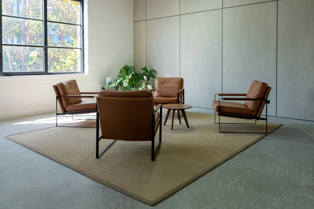 Tan leather lounge chairs and planting in a quiet breakout zone, Clinibase office fitout, Collingwood.