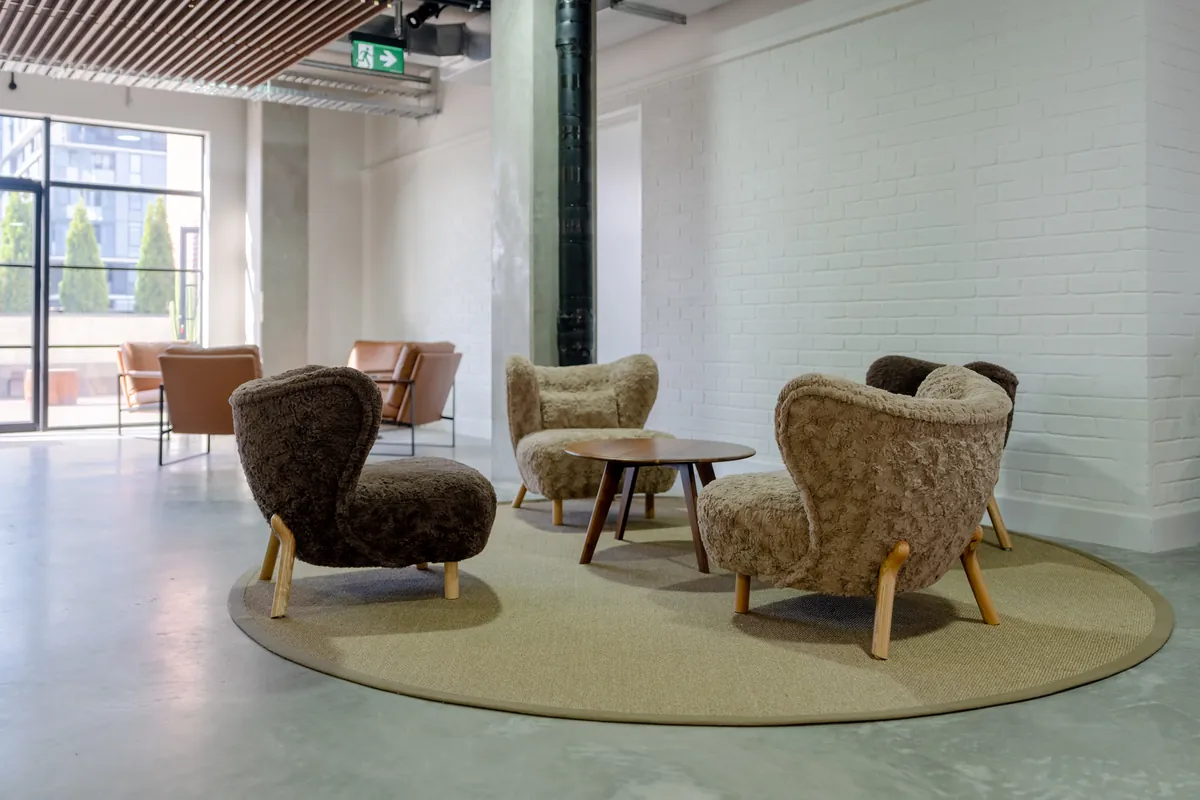 Soft shearling lounge chairs on a round rug in a breakout area, Clinibase office fitout, Collingwood.