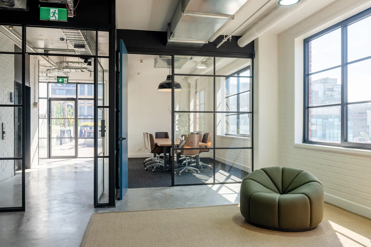 Glass-partitioned meeting room off a breakout area near the entrance, Clinibase office fitout, Collingwood.