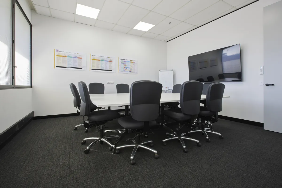 Boardroom with meeting table, chairs and wall-mounted screen at the CPB Contractors office fitout, Blackburn North.