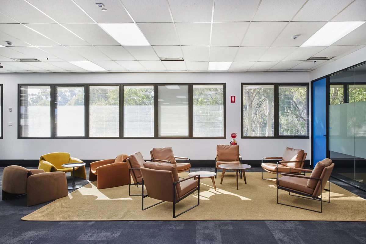 Breakout lounge with tan leather armchairs and rug at the CPB Contractors office fitout, Blackburn North.