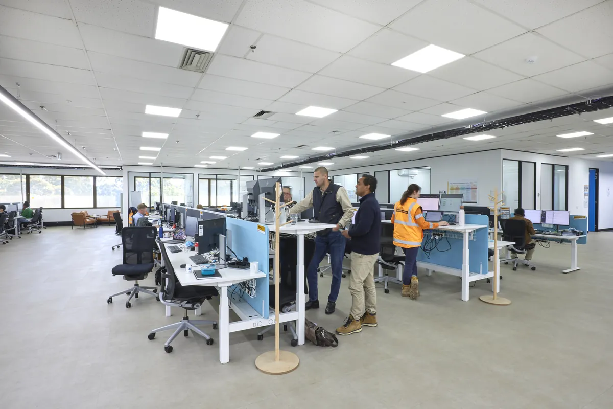 Staff collaborating at sit-stand workstations in the open-plan area, CPB Contractors office fitout, Blackburn North.