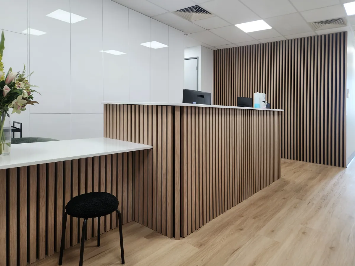 Angled view of the timber batten reception desk at the Creative Smiles dental clinic fitout, Armadale.
