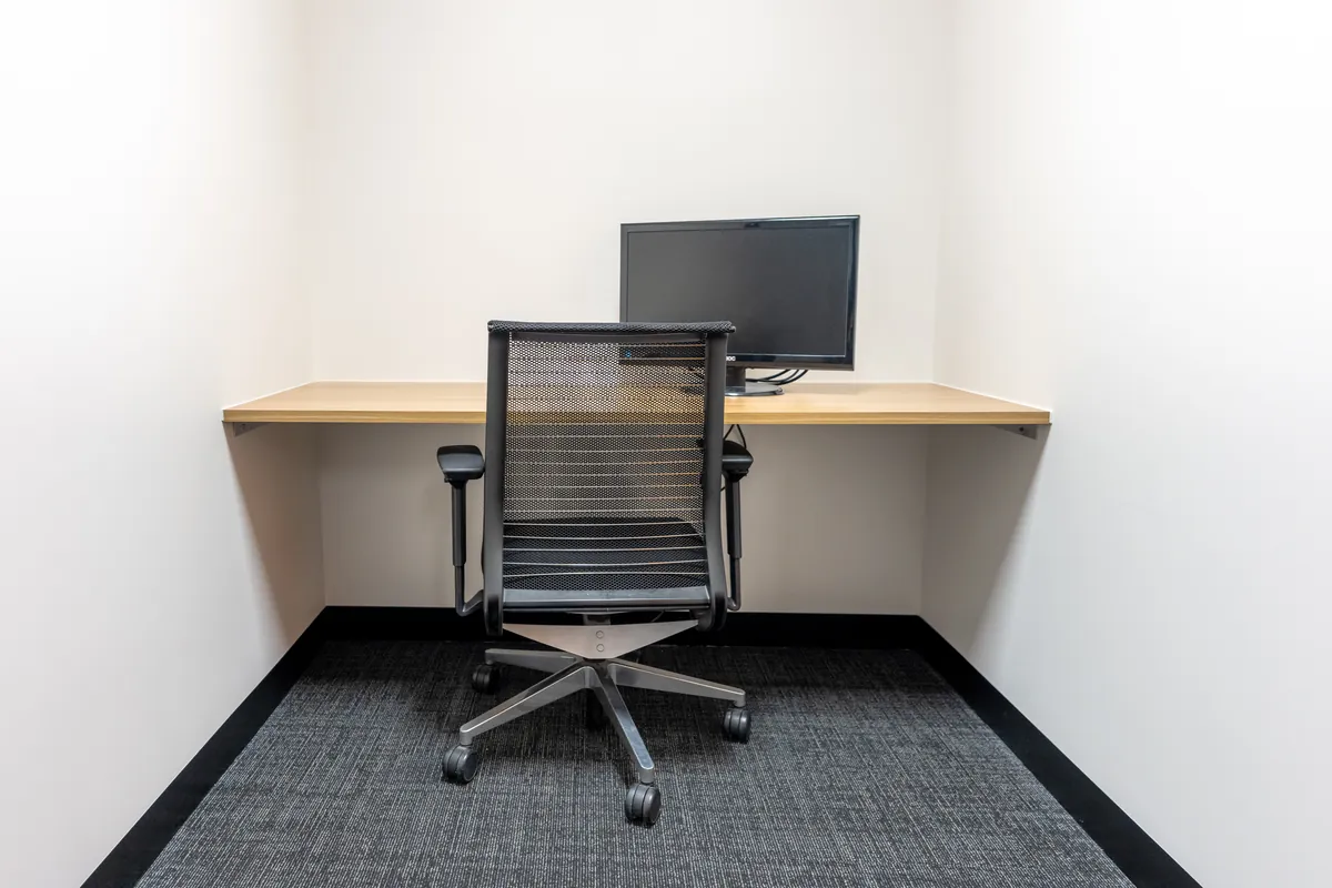 Compact focus room with timber wall desk, task chair and monitor at the Empower Wealth office fitout, North Melbourne.
