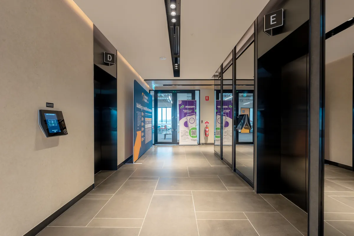 Tiled lift lobby with branded signage and access control at the Empower Wealth office fitout, North Melbourne.