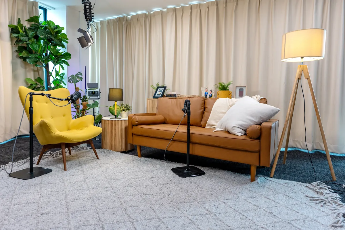 Podcast studio recording setup with leather sofa, yellow armchair and mic stands at the Empower Wealth office fitout, North Melbourne.