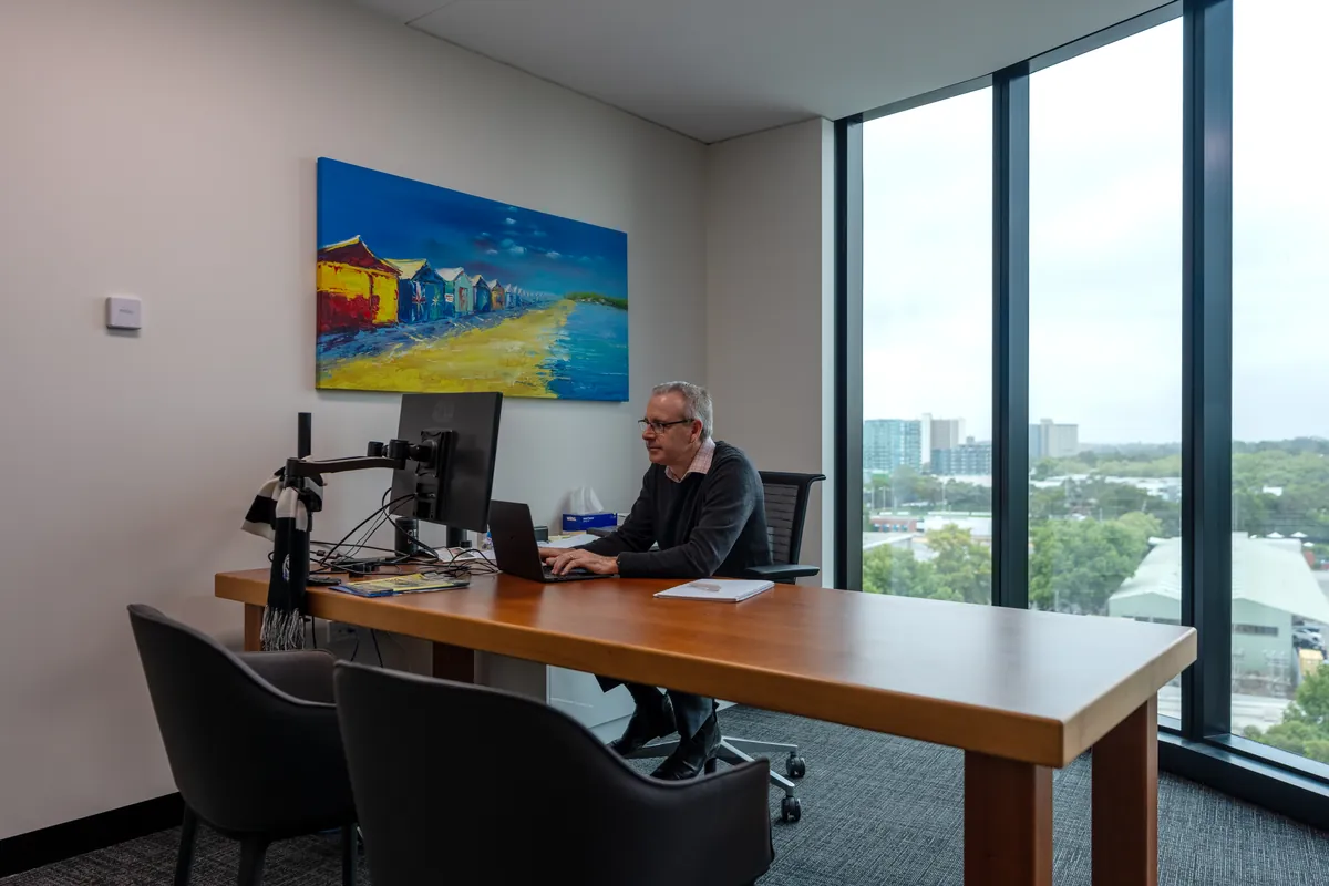 Private office with timber desk, monitor and city views at the Empower Wealth office fitout, North Melbourne.