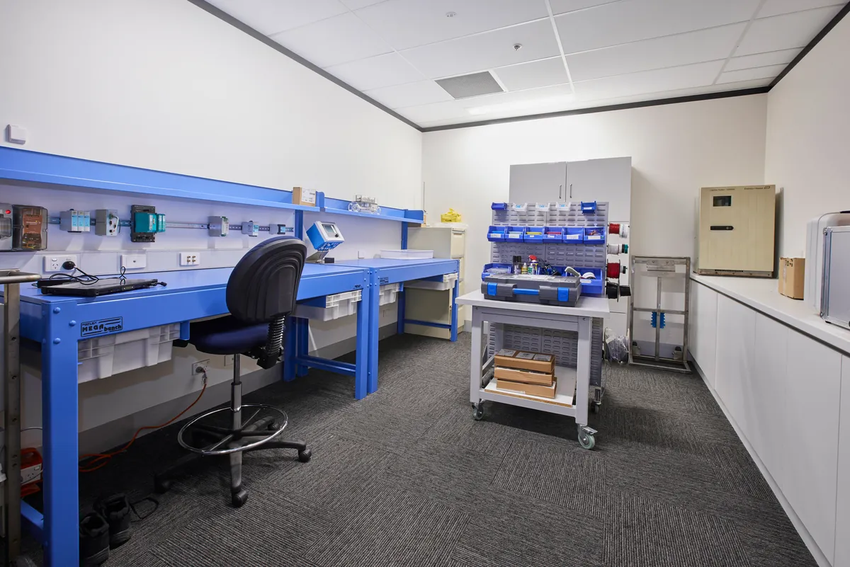 Technical workshop with blue workbenches and instrument displays at the Endress and Hauser office fitout, Mulgrave.