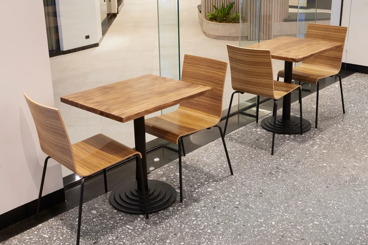Timber cafe tables and chairs on terrazzo flooring at the Exchange Tower office refurbishment, Melbourne.