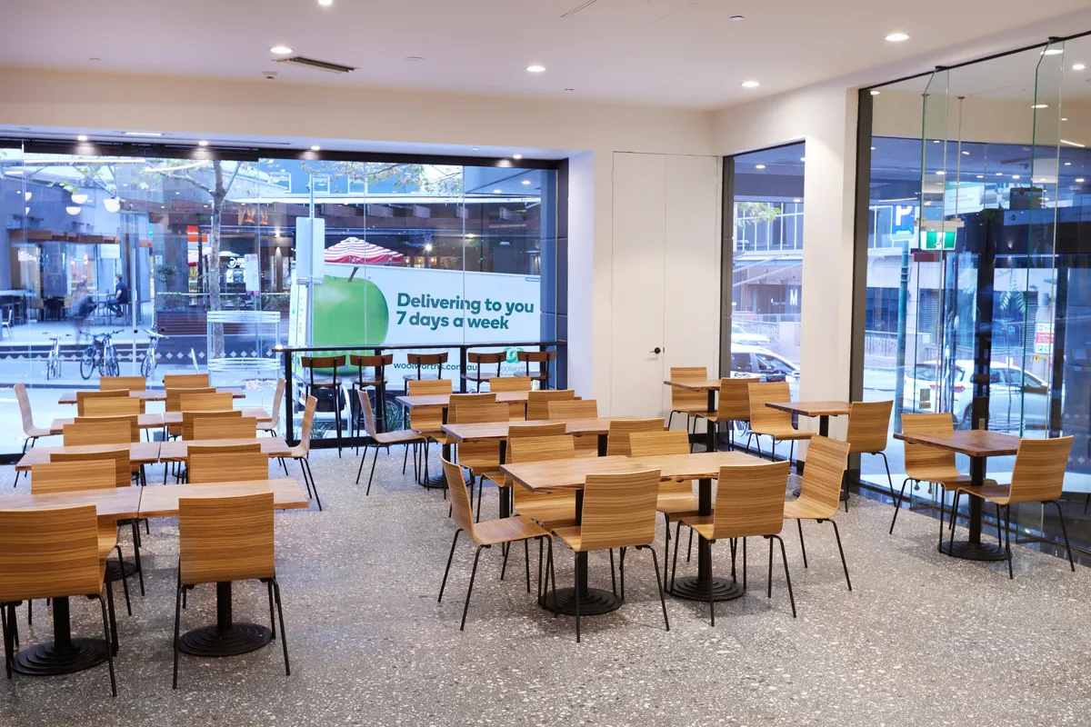 Timber cafe dining seating beside full-height glazing at the Exchange Tower office refurbishment, Melbourne.