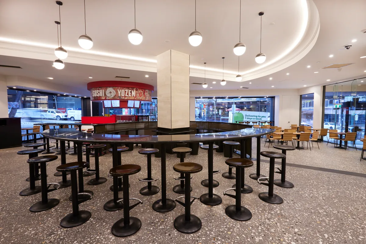 Food court dining hub with circular bar stools and retail tenancies at the Exchange Tower refurbishment, Melbourne.