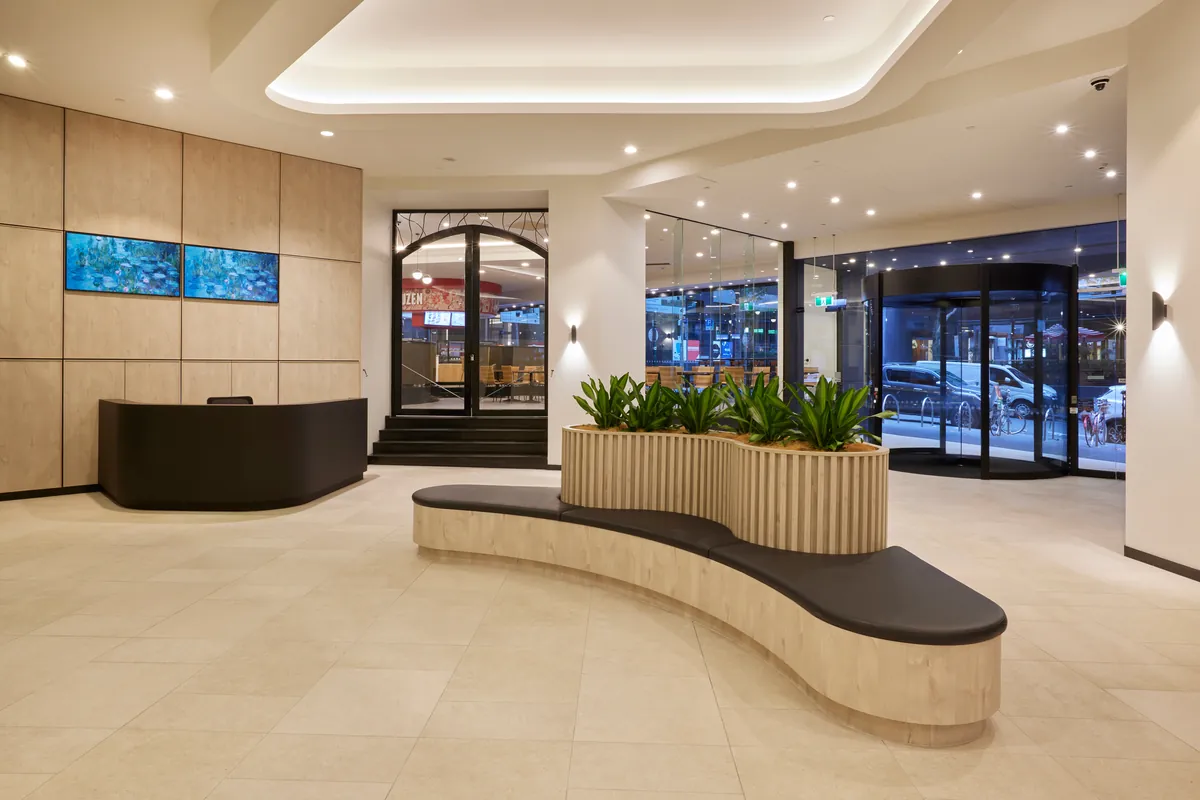 Refurbished foyer with concierge desk, curved timber bench planter and street entry at Exchange Tower, Melbourne.