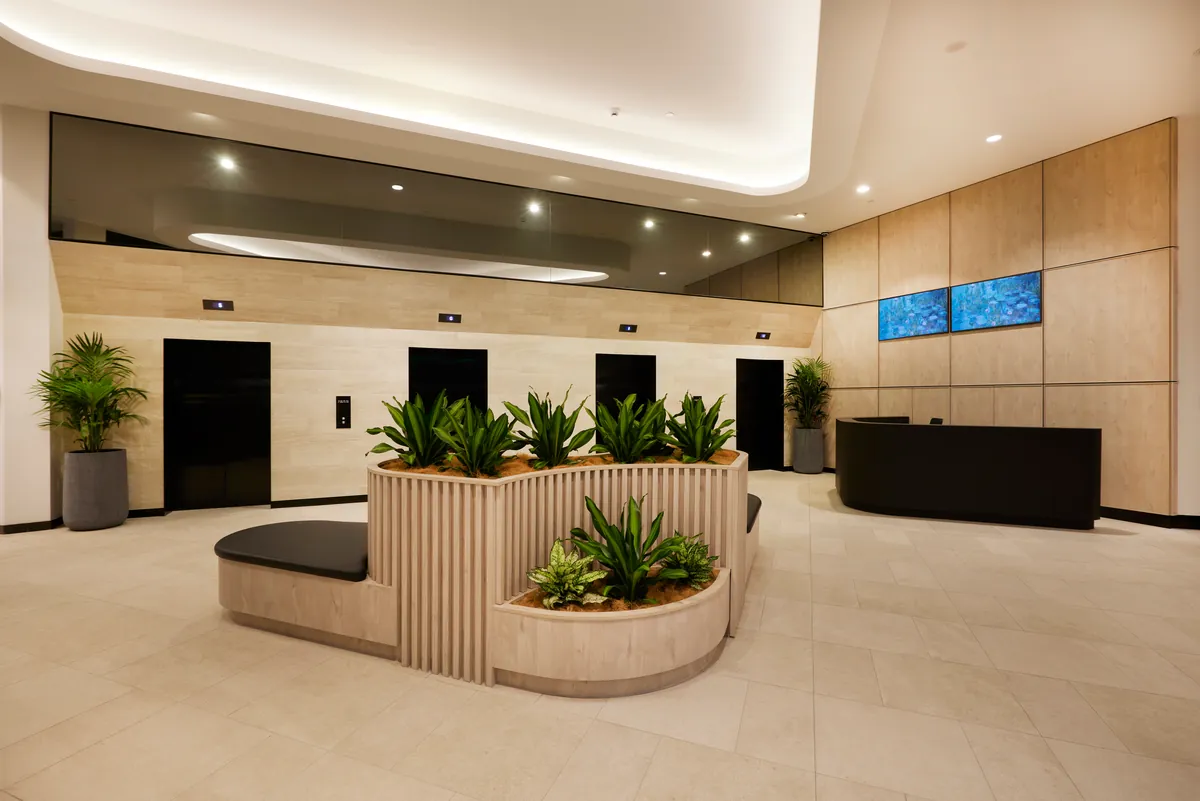 Lift lobby with timber-clad walls, planter bench and concierge desk at the Exchange Tower refurbishment, Melbourne.