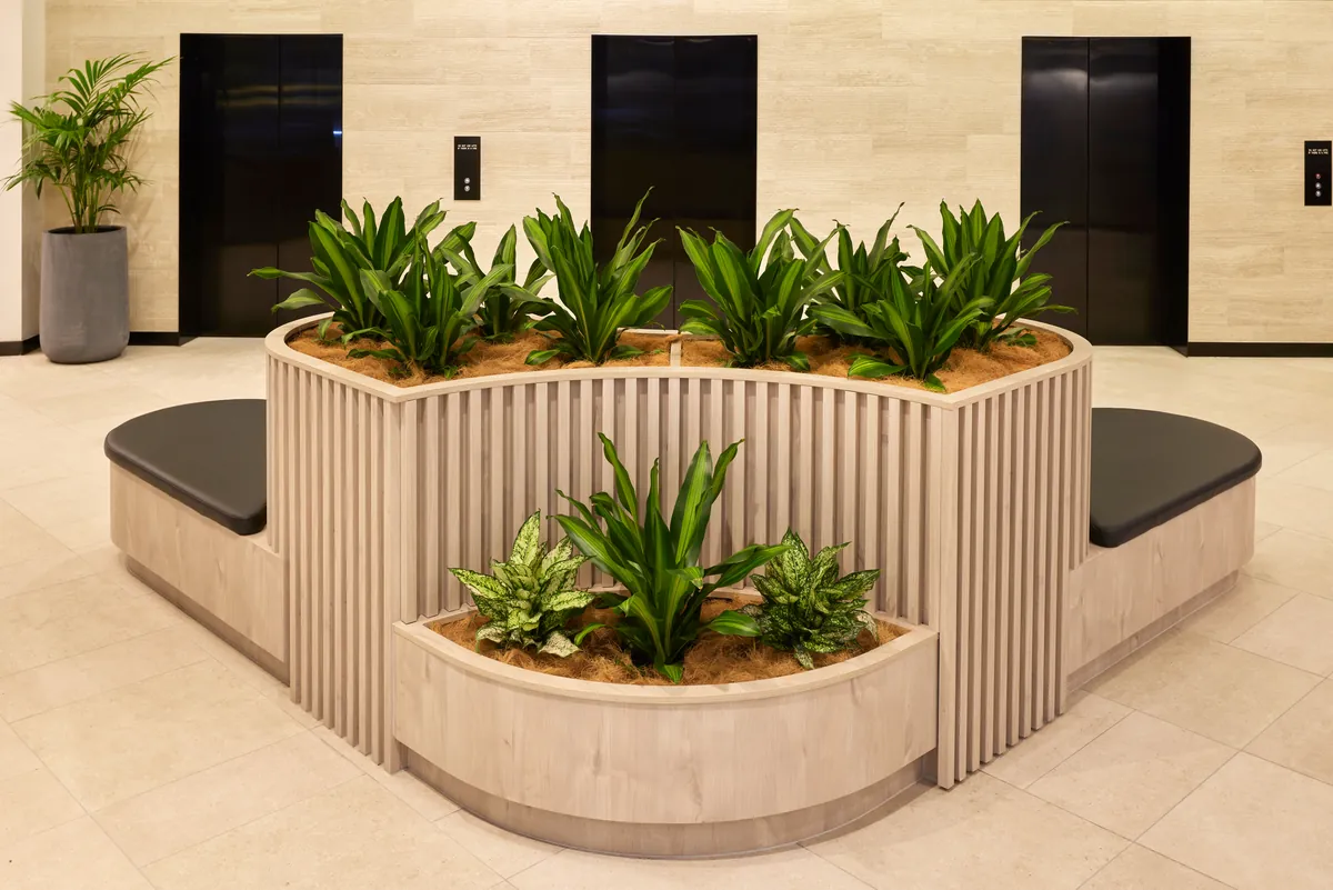 Curved timber-battened planter and bench seating between lift doors at the Exchange Tower lobby refurbishment, Melbourne.