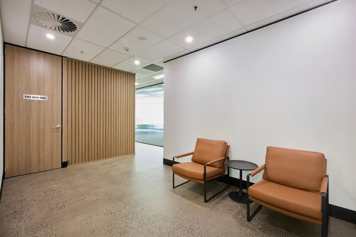 Reception lounge with timber slat wall and tan leather chairs, Growthpoint spec suite fitout, Mulgrave.