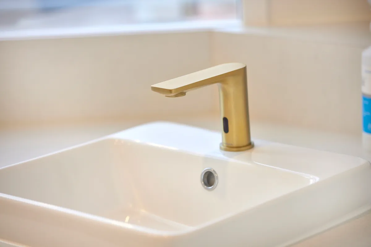Brass sensor tapware and basin detail in the amenities at the Kew Periodontics dental clinic fitout, Kew.