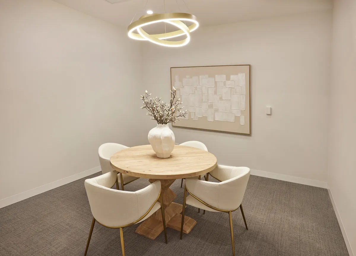 Carpeted consult room with round table and ring pendant light at the Kew Periodontics dental clinic fitout, Kew.