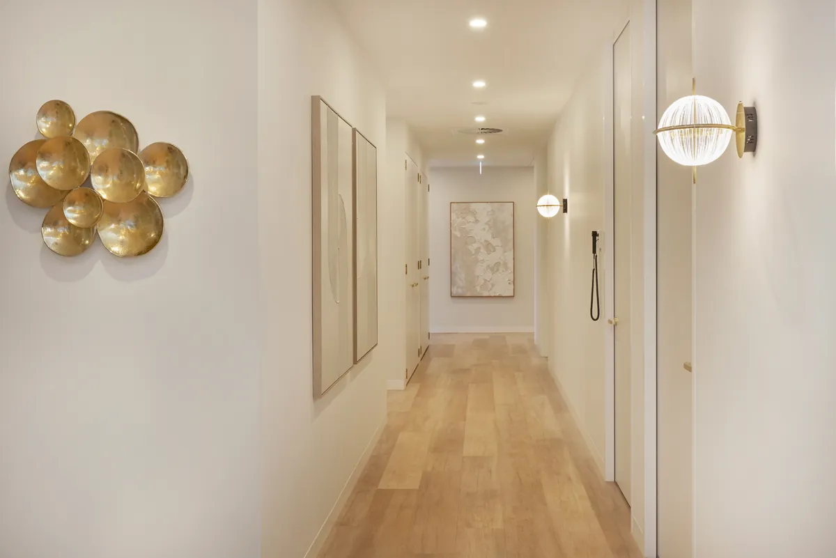 Naturally lit corridor with feature artwork and brass sconces at the Kew Periodontics dental clinic fitout, Kew.