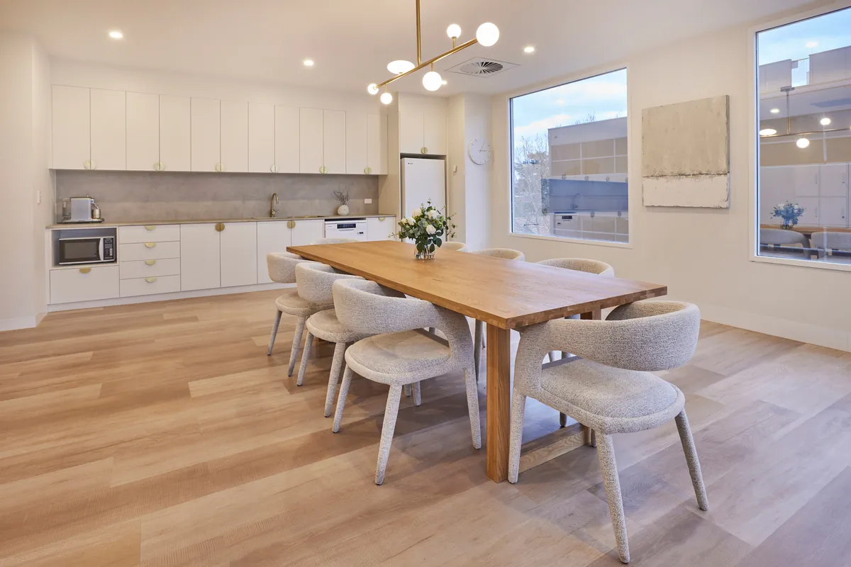 Staff kitchen and dining table with timber detailing at the Kew Periodontics dental clinic fitout, Kew.