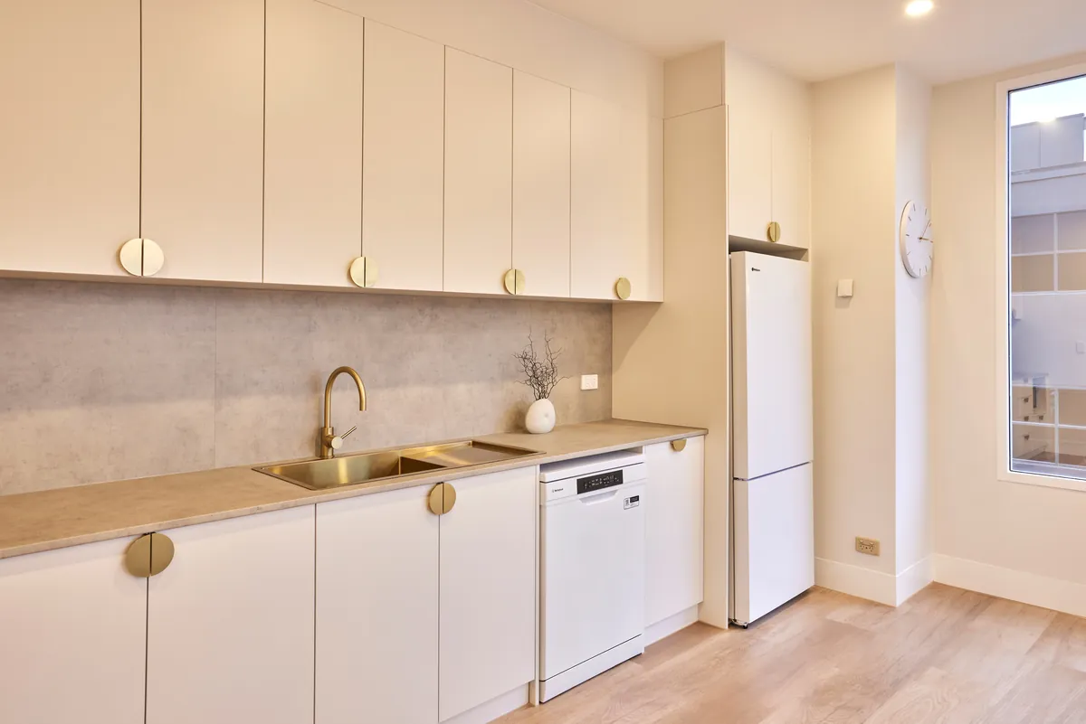 Staff kitchenette with brass tapware and integrated appliances at the Kew Periodontics dental clinic fitout, Kew.