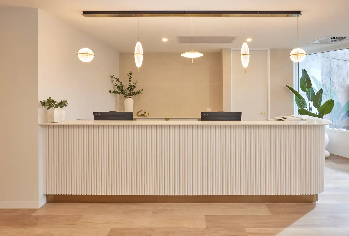 Custom fluted reception desk with pendant lighting at the Kew Periodontics dental clinic fitout, Kew.
