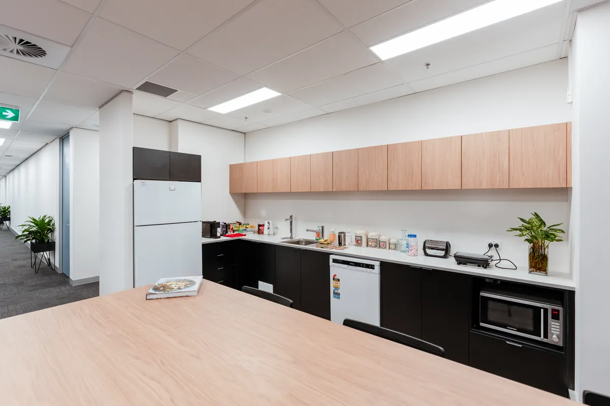 Staff kitchen with timber overhead joinery and dining bench at the McLarens office fitout, Melbourne.