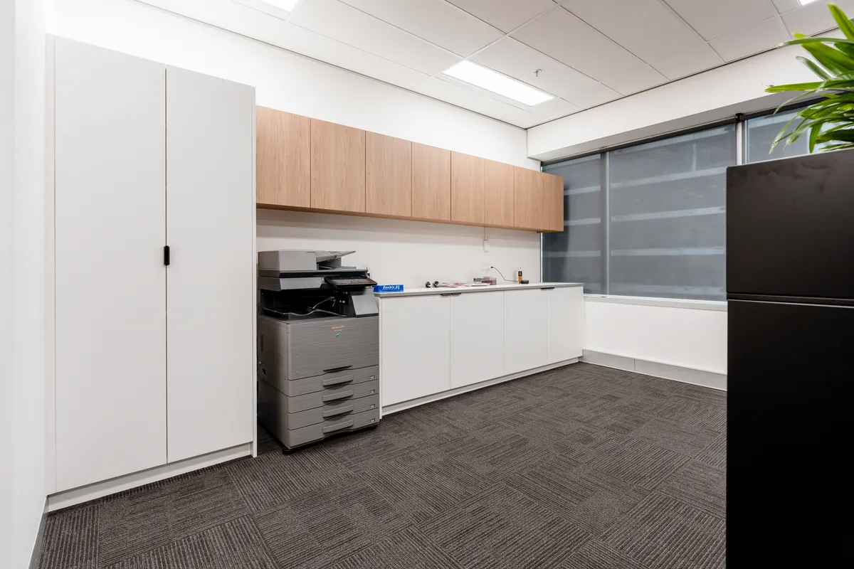 Utility area with printer station, overhead joinery and storage cupboards at the McLarens office fitout, Melbourne.