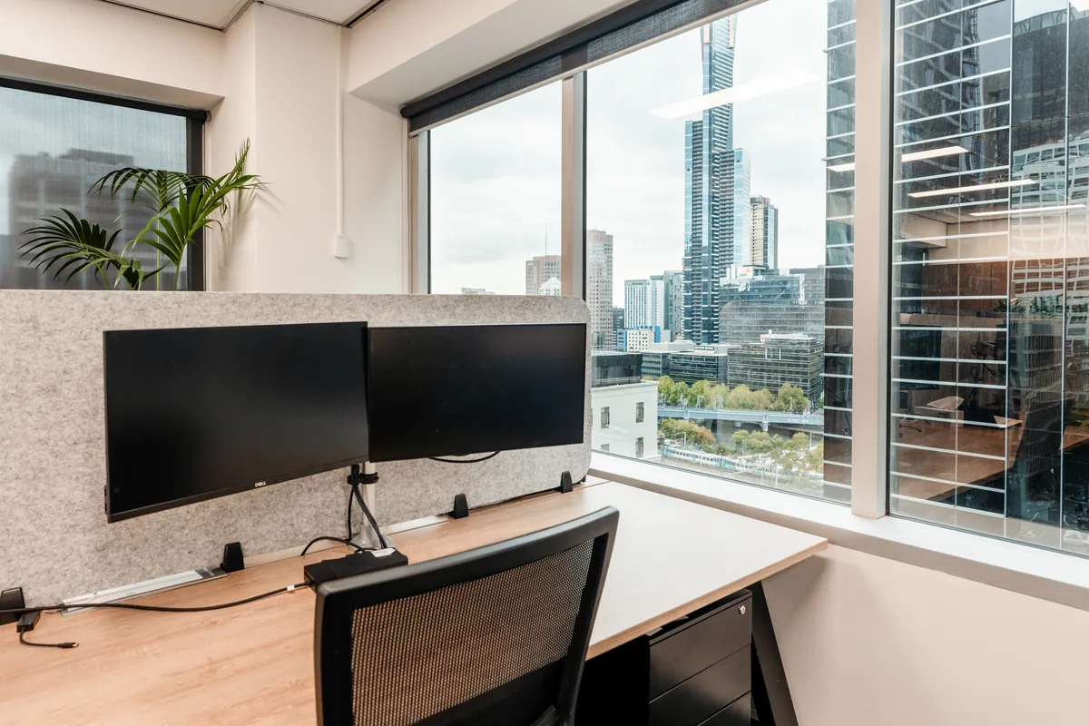 Private office workstation with dual monitors and city skyline views at the McLarens office fitout, Melbourne.