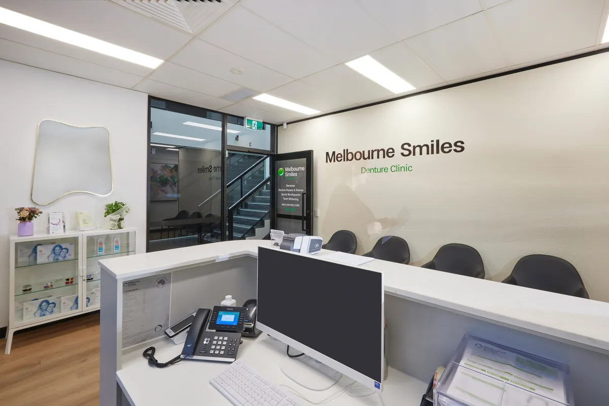 Reception desk with display cabinets and branded wall at the Melbourne Smiles dental clinic fitout, North Caulfield.