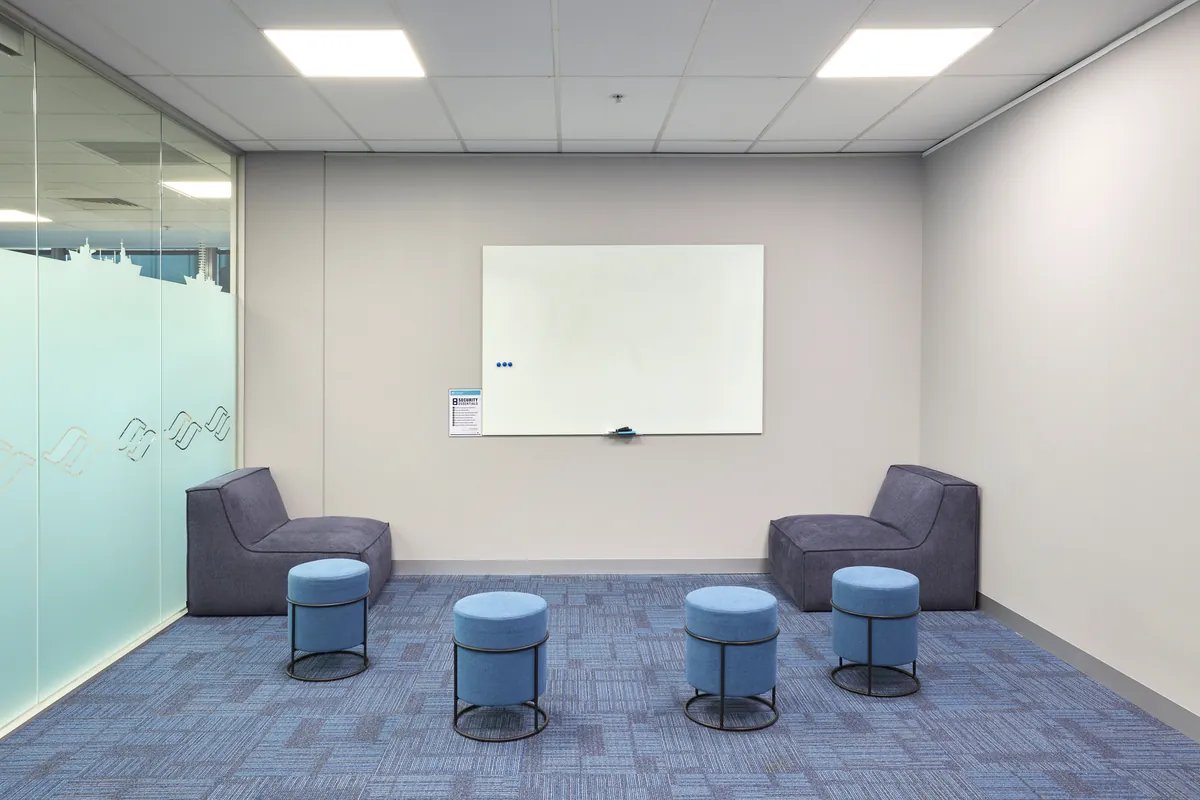 Informal breakout area with whiteboard, lounge chairs and stools at the Navantia office fitout, Docklands.