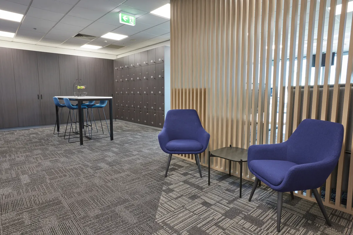 Breakout zone with timber batten screen, lockers and lounge chairs at the Navantia office fitout, Docklands.
