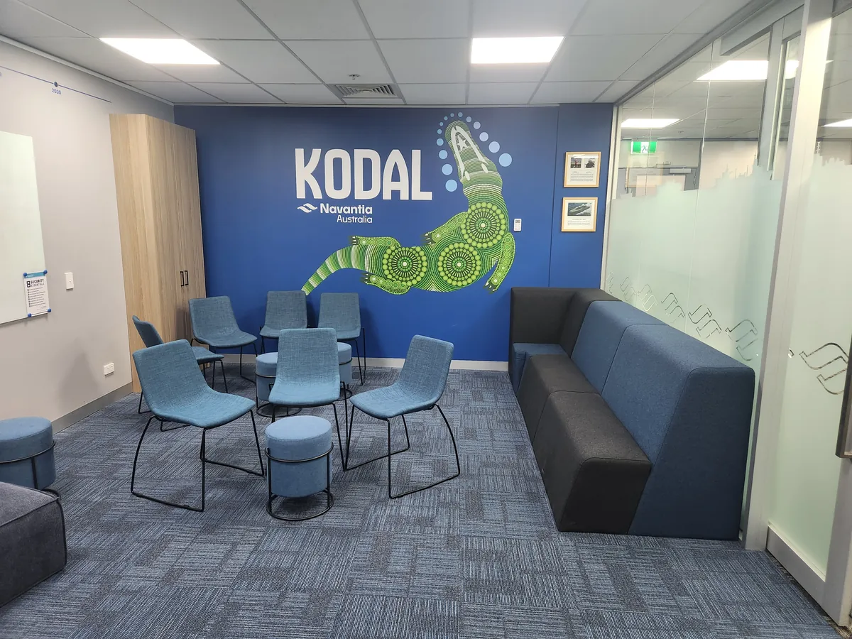 Kodal breakout space with blue feature wall, soft seating and stools at the Navantia office fitout, Docklands.
