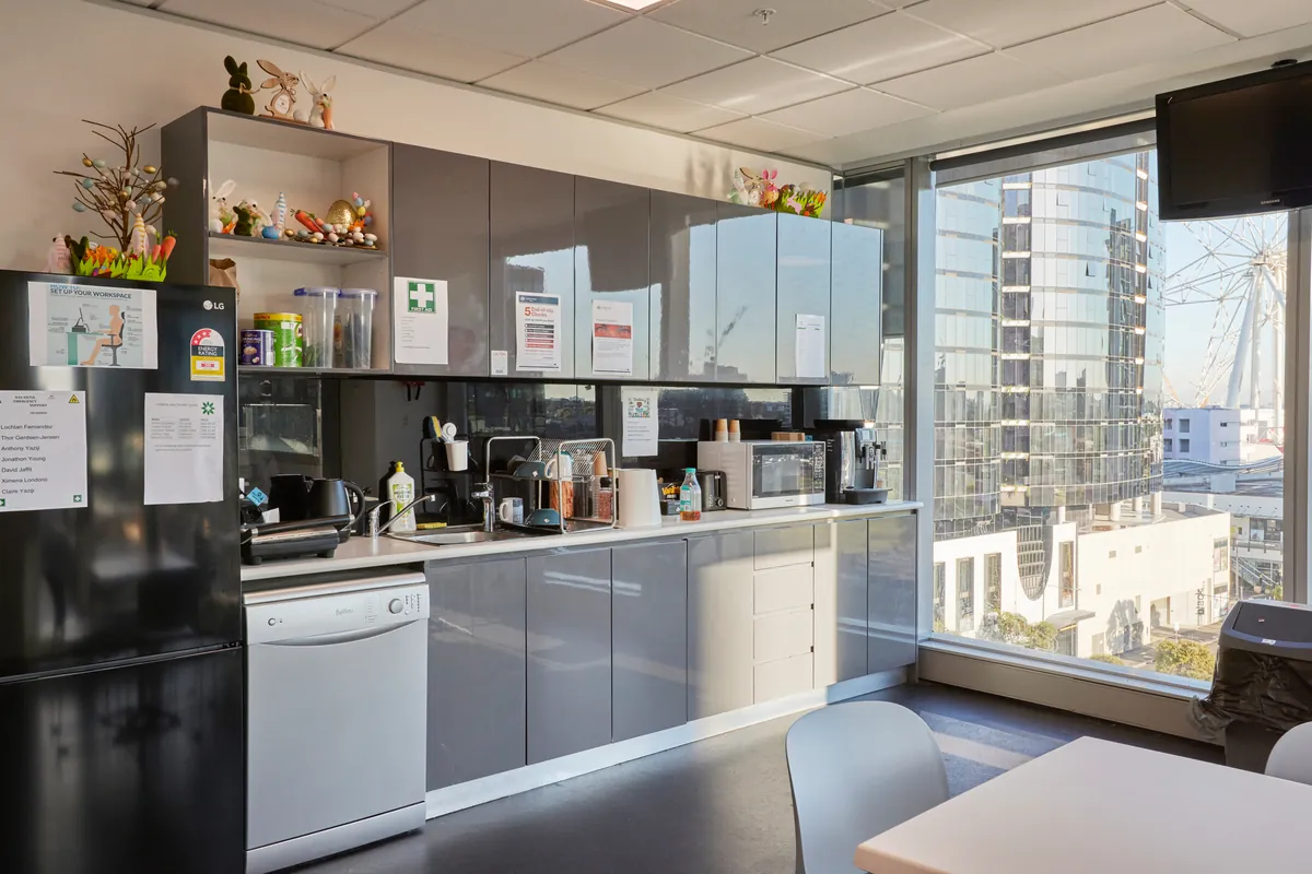 Staff kitchen with grey joinery, appliances and window outlook at the Navantia office fitout, Docklands.