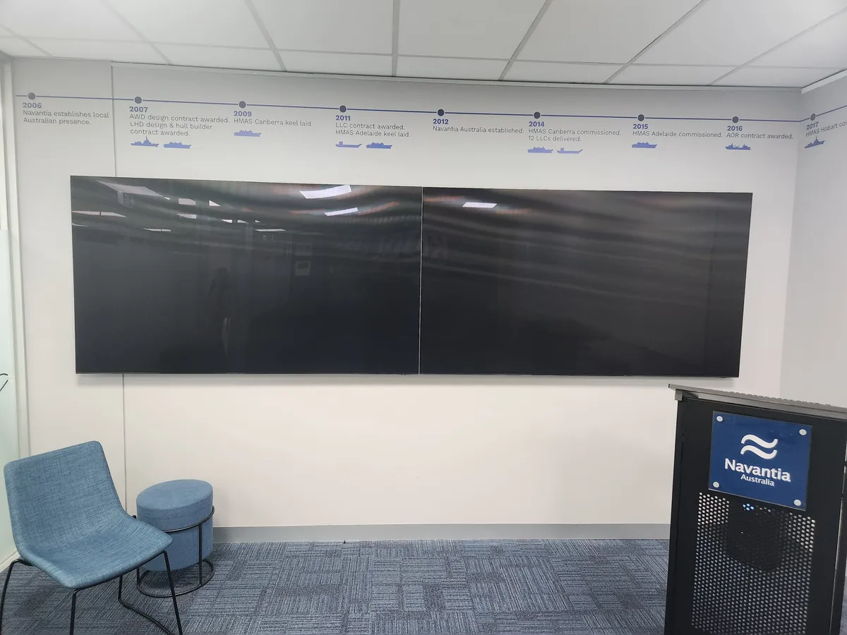 Meeting room with dual screens, timeline graphic and Navantia lectern at the Navantia office fitout, Docklands.