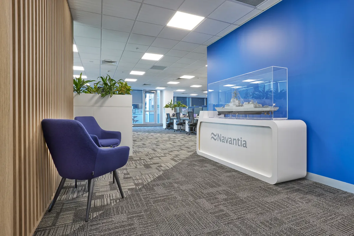 Reception desk with Navantia signage, ship model and lounge chairs at the Navantia office fitout, Docklands.