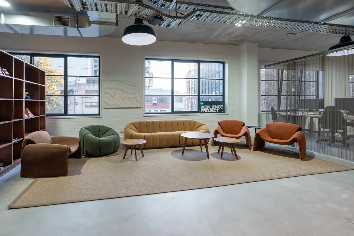 Breakout lounge with branded signage and soft seating, Resilience Project office fitout, Collingwood.