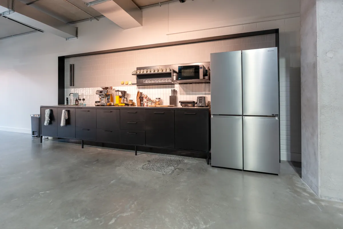 Kitchen with black joinery and coffee station at the Resilience Project office fitout, Collingwood.