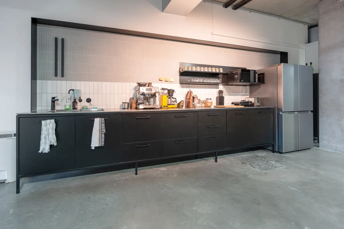 Custom black kitchen joinery with coffee station at the Resilience Project office fitout, Collingwood.