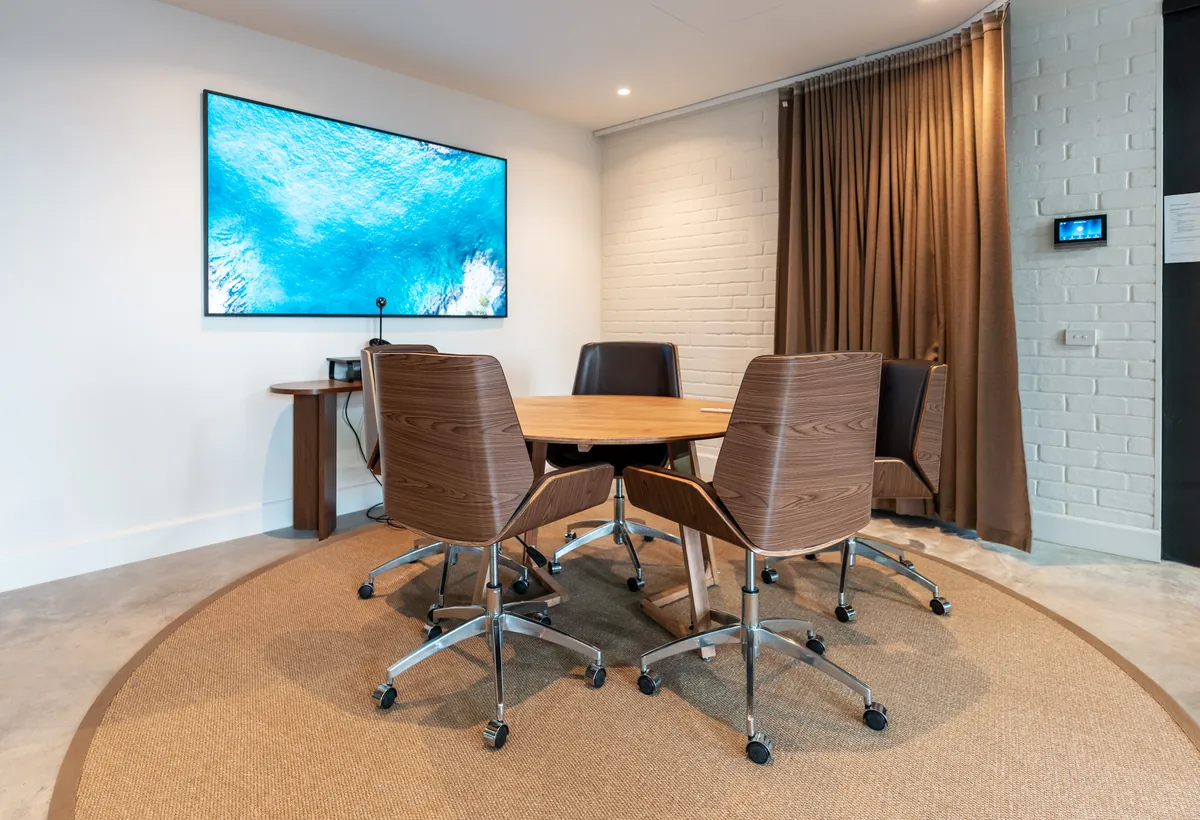 Meeting room with round timber table and wall-mounted screen, Resilience Project office fitout, Collingwood.